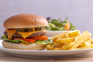 Burger in a bun with chips and salad
