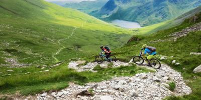 Mountain biking in the Lake District countryside Two mountain bikers riding down a hill