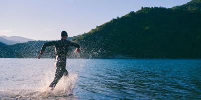 Wild swimming in the Lake District Swimmer wearing a wetsuit wading into a lake