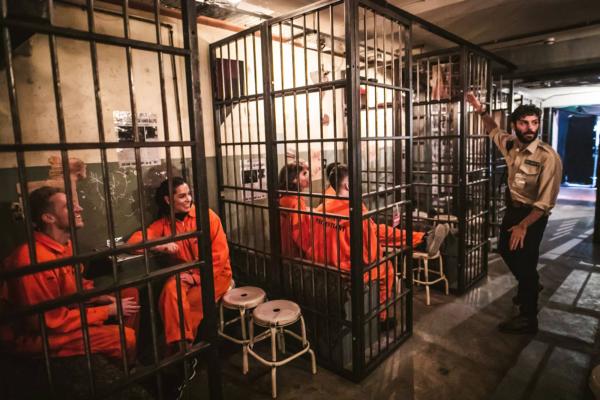 Groups of adults wearing orange jumpsuits behind bars