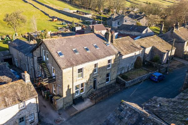 Stone hostel building with houses and green rolling hills in the background