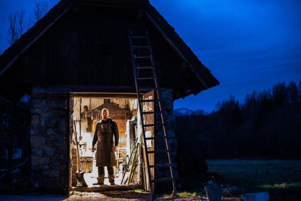 Blacksmith in rural forge, at twilight