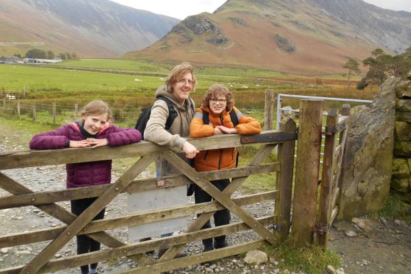 Dad and two children leaning on a wooden gate in the countryside