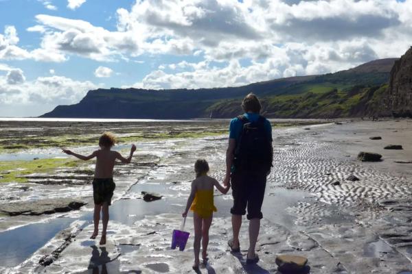 Dad and two children walking on wet sand on a beach