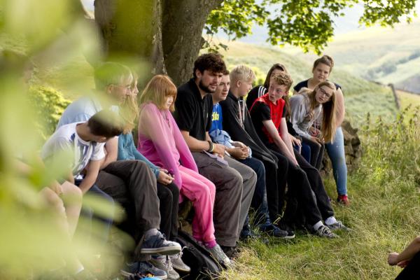 Group of young people on a YHA trip sitting in the countryside