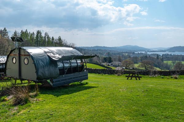 Glamping Landpod on a grass field overlooking a lake