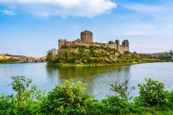 Pembroke Castle surrounded by a lake in Pembroke, Wales, UK