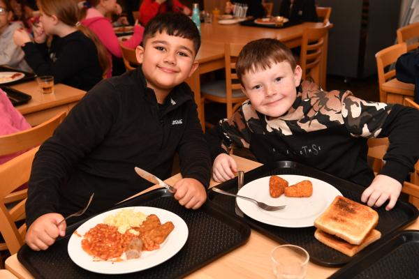 Two smiling boys eating a cooked breakfast