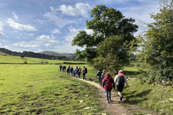 Walkers walking across fields in Hartington on a sunny day