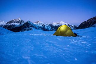 Tent with camping light on in the snow on a mountain 