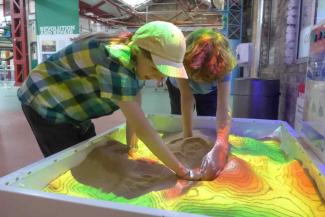 Siblings playing with sand at museum