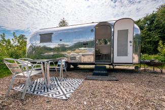 Silver caravan with open door and metal seating