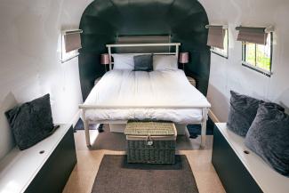 Inside a caravan with a double bed covered with white bedding