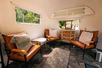 Inside a caravan with brown leather armchairs and a wooden chest of drawers