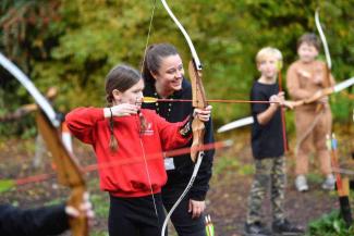 Children practising archery with an instructor