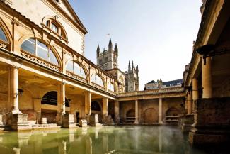 Open-air Roman spa bath surrounded by historic buidlings including a cathedral