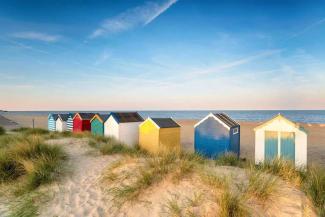 Colourful painted beach huts in sand dunes