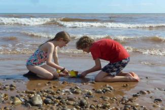 Young boy and girl building sandcastles on a beach