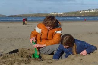 Boy wearing an orange jacket and a girl playing on the beach