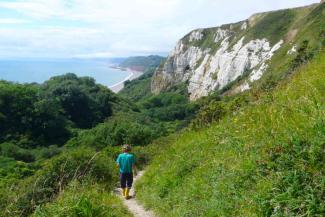 Young boy walking down a coastal path surrounded by trees