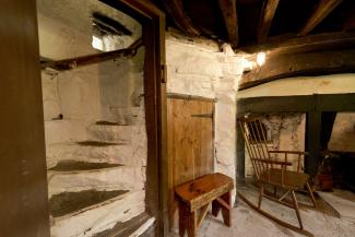 Stone room with wooden beans and furniture and steps leading upstairs