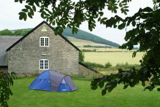 Camping tent by a hostel building with countryside in the background