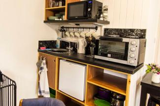 Kitchen counter with a small fridge, microwave and kettle