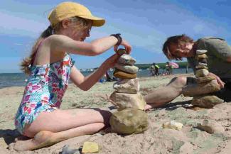 Child and father on the beach playing with stones