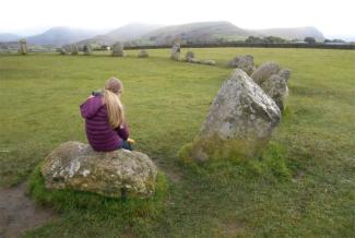 Child sitting on a large boulder in a stone circle