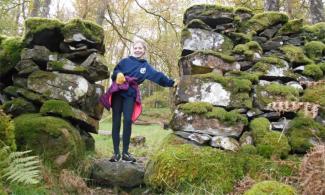 Child smiling between two moss-covered stone walls