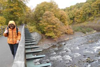 Child crossing a bridge while wearing an orange coat