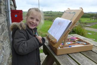 Child drawing outside a hostel in the countryside