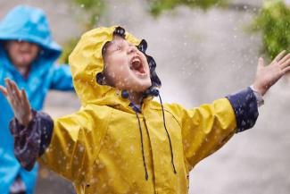 Child wearing a yellow raincoat in the rain