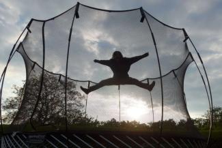 Child jumping on a trampoline at sunset