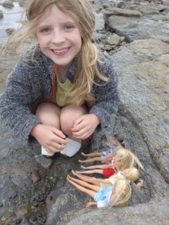 Child smiling playing with dolls on Whitby beach