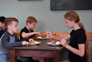 Children eating breakfast on a wooden table