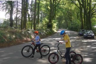 Boy and girl pushing bikes across a country lane