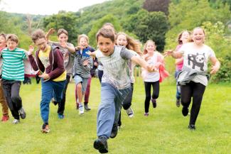 Group of children running across a grass field