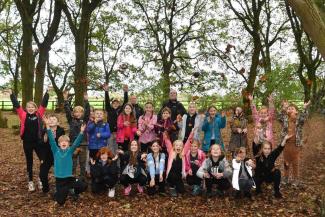 Group of children throwing leaves in a forest