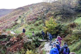 Children walking up a hill in the rain