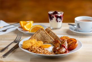 Full English breakfast with orange slices and fruit yogurt on the side