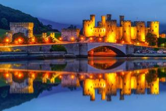 Impressive castle lit up at dusk with views over a river