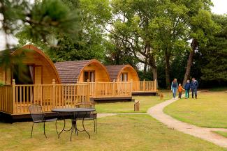 Family walking by a row of wooden camping pods