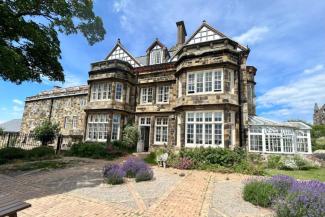 Large mansion building with stone walls and white wooden window frames