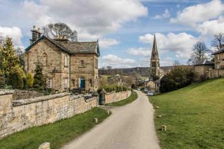 Pretty Derbyshire village with stone houses and a tall church with a spire