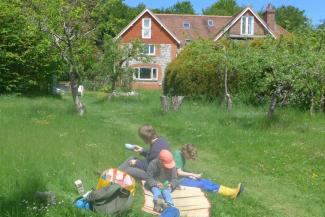 Family group sitting on the grass outside a hostel building