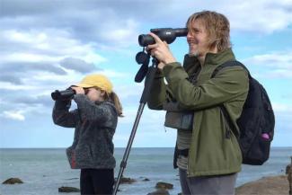 Father and daughter watching with bionoculars on the beach