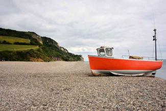 Orange fishing boat moored on a pebbled beach