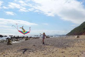 Young girl flying a rainbow kite on a beach