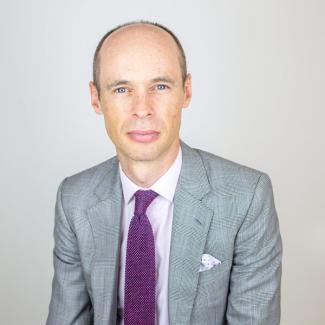 Man wearing a grey suit with a purple tie